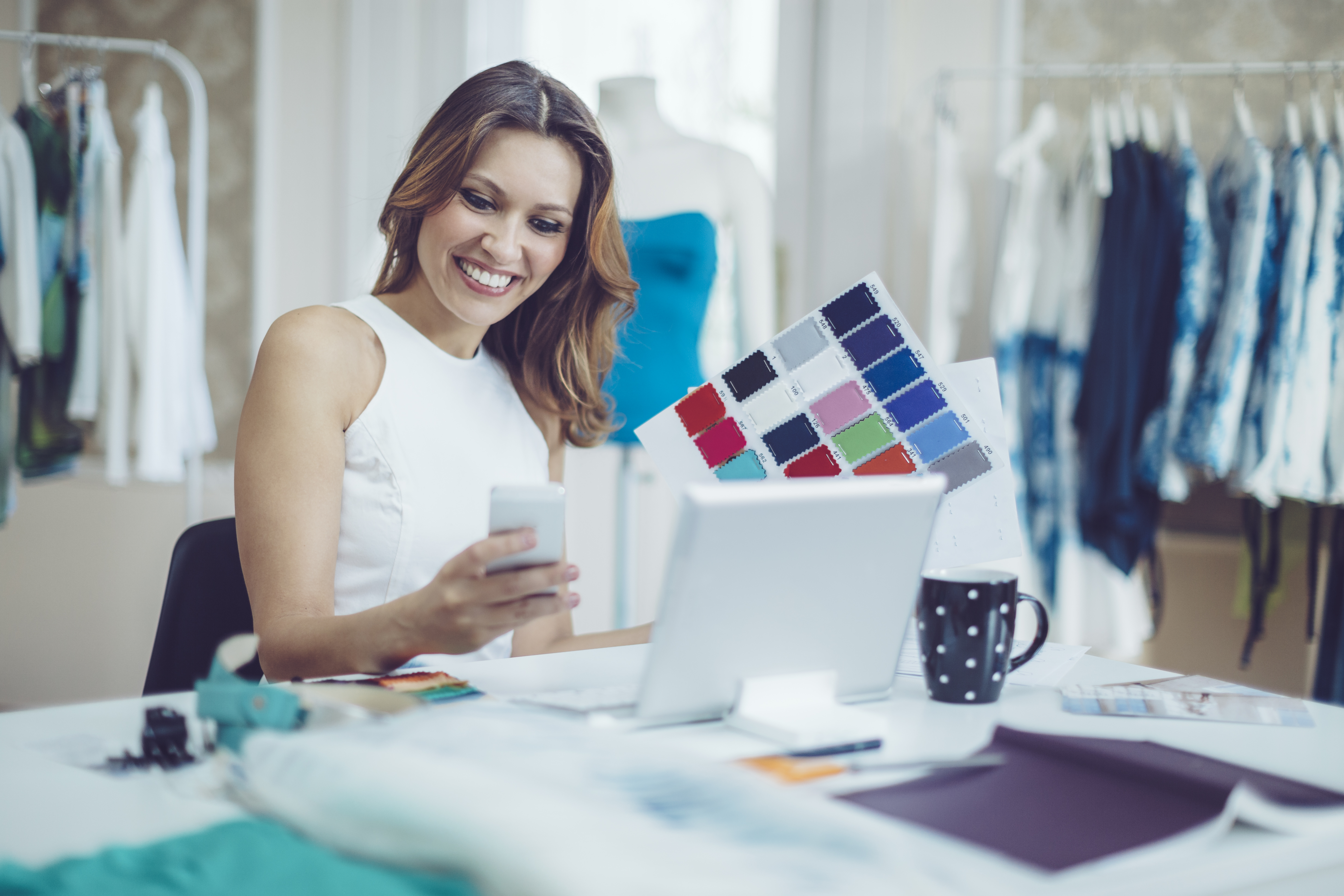 Woman smiling at laptop while holding color swatches