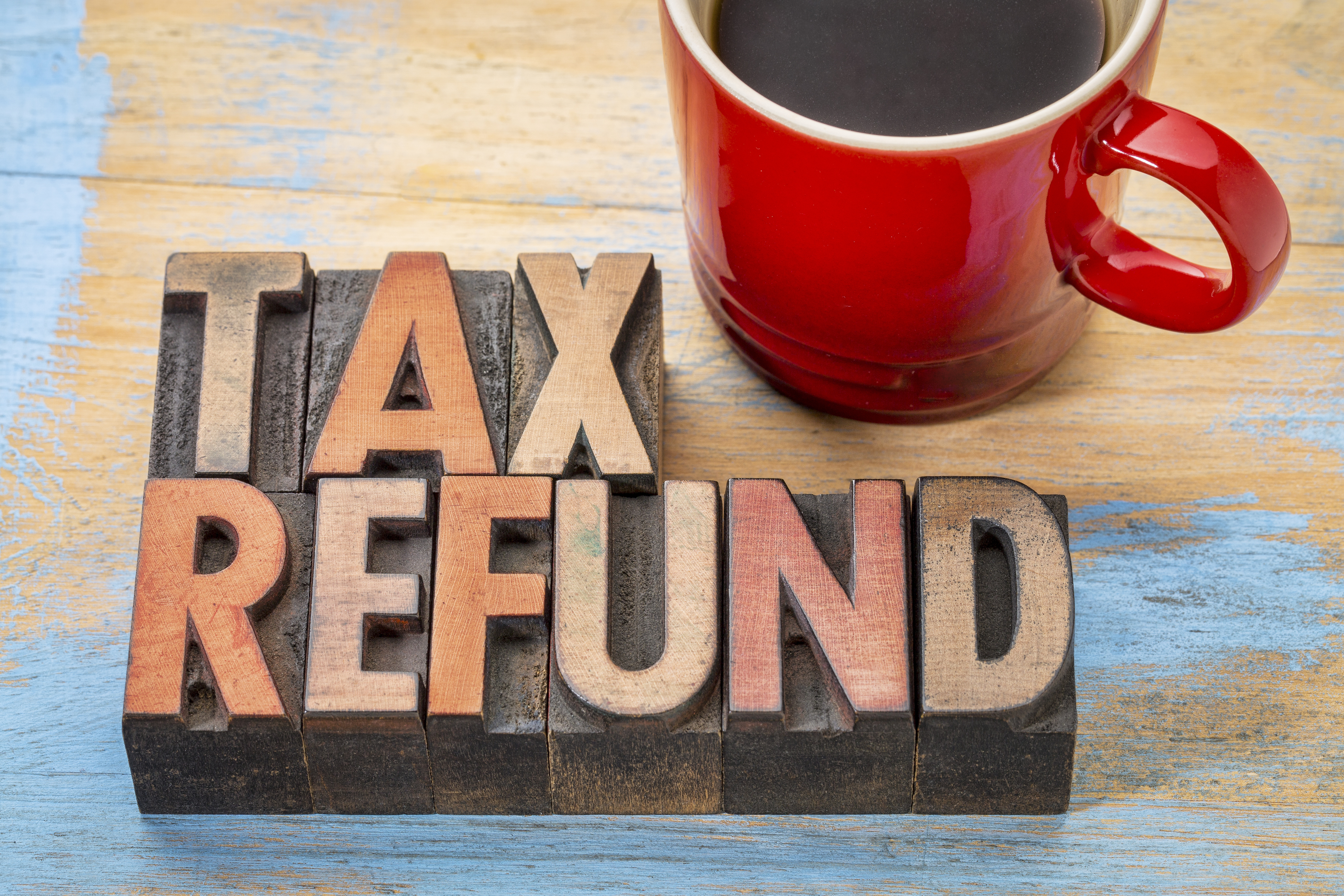 tax refund in wood letters on table with red coffee mug