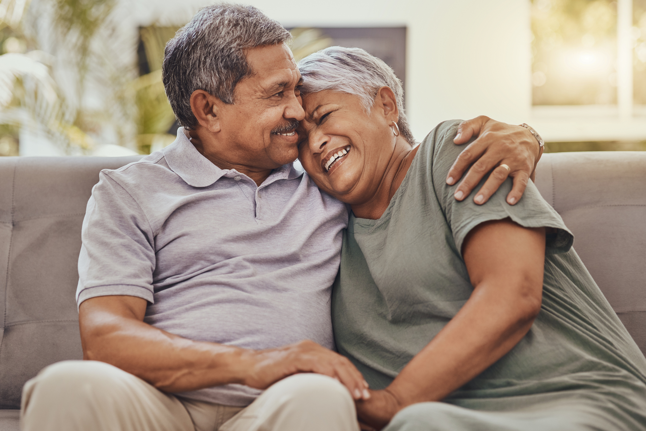older black couple hugging and laughing on couch