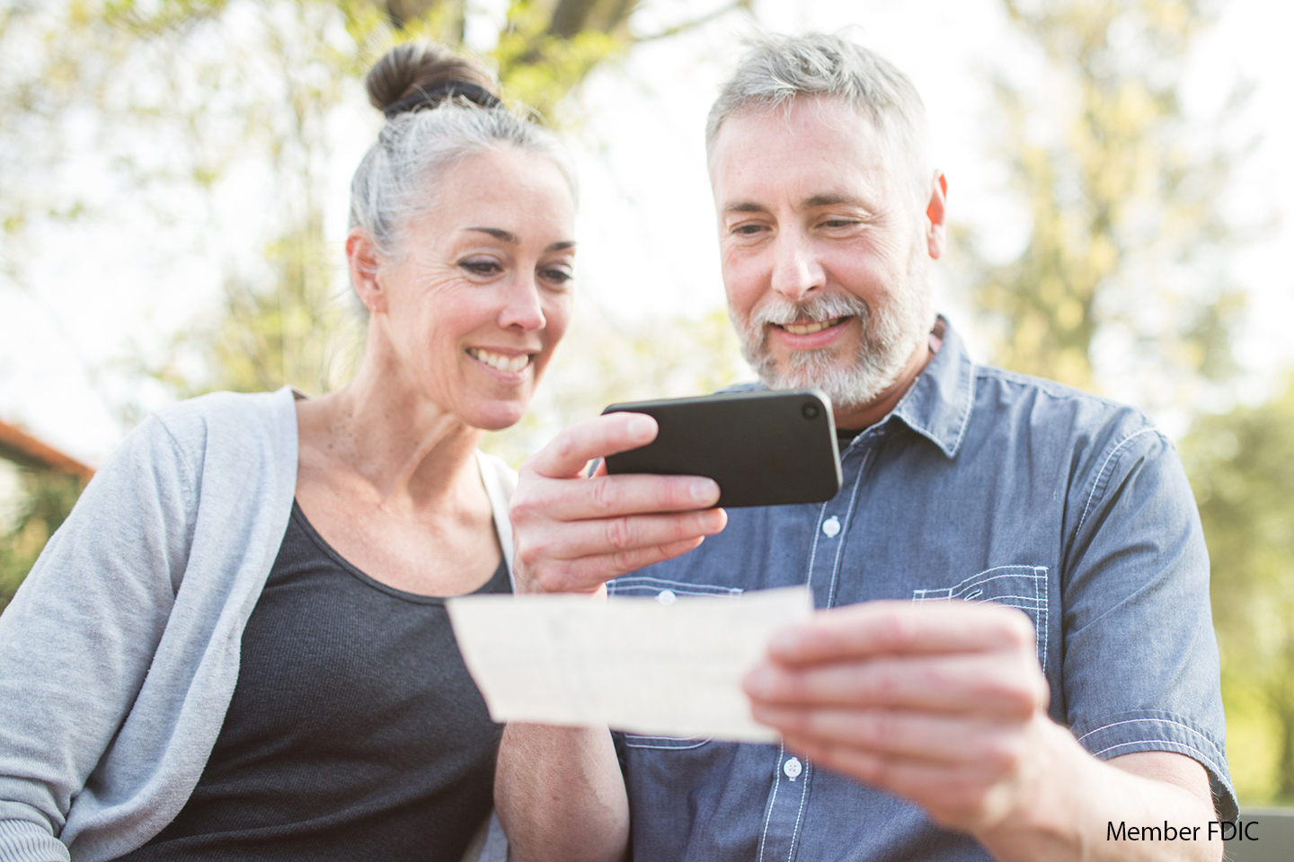 older couple taking a picture of check on phone