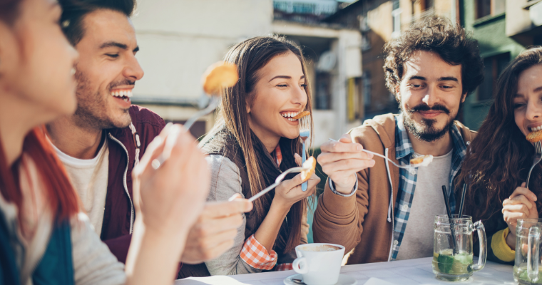 group of young adult friends eating and laughing together 