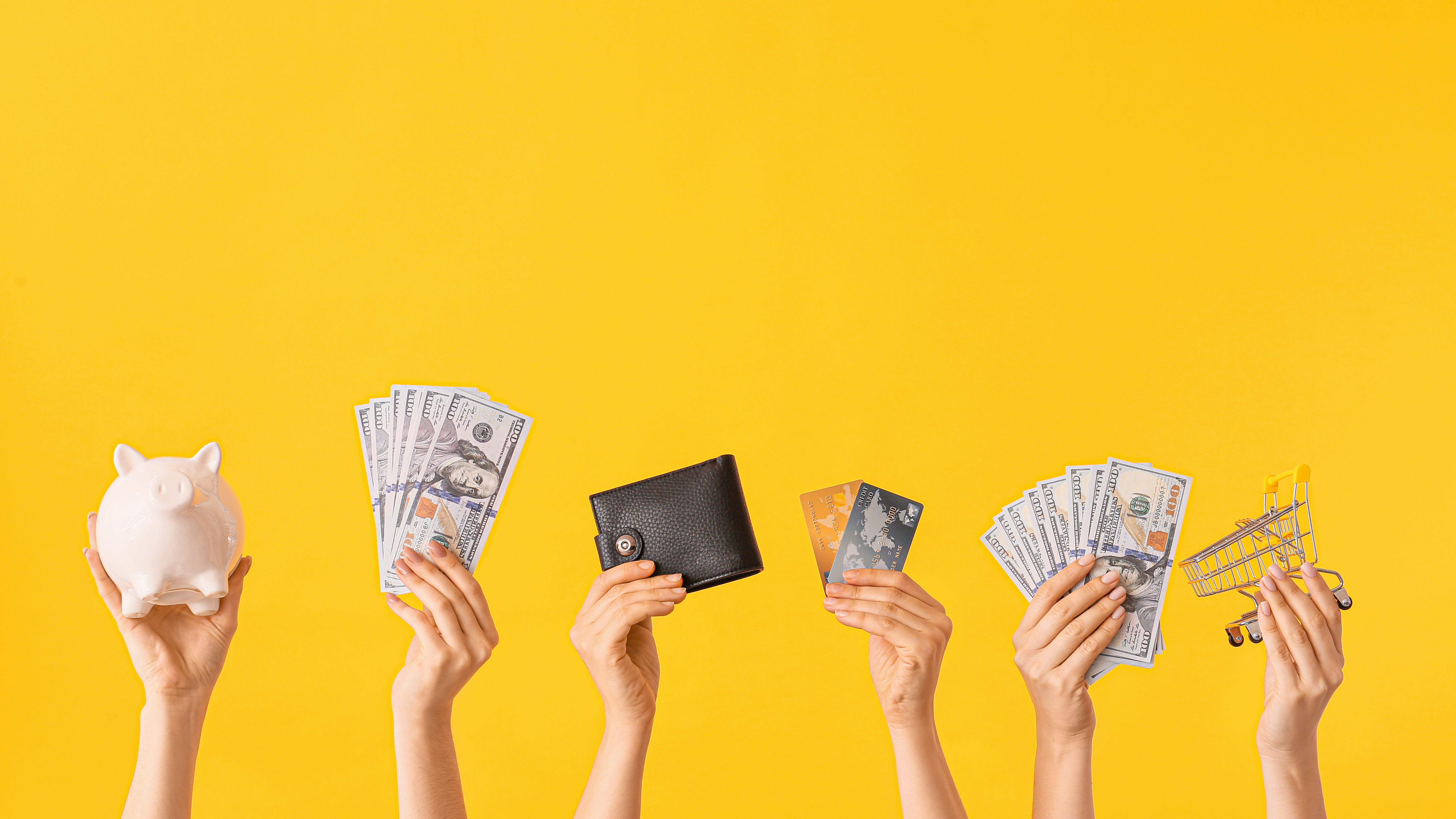 hands holding piggy bank, money, wallet, cards in front of yellow background