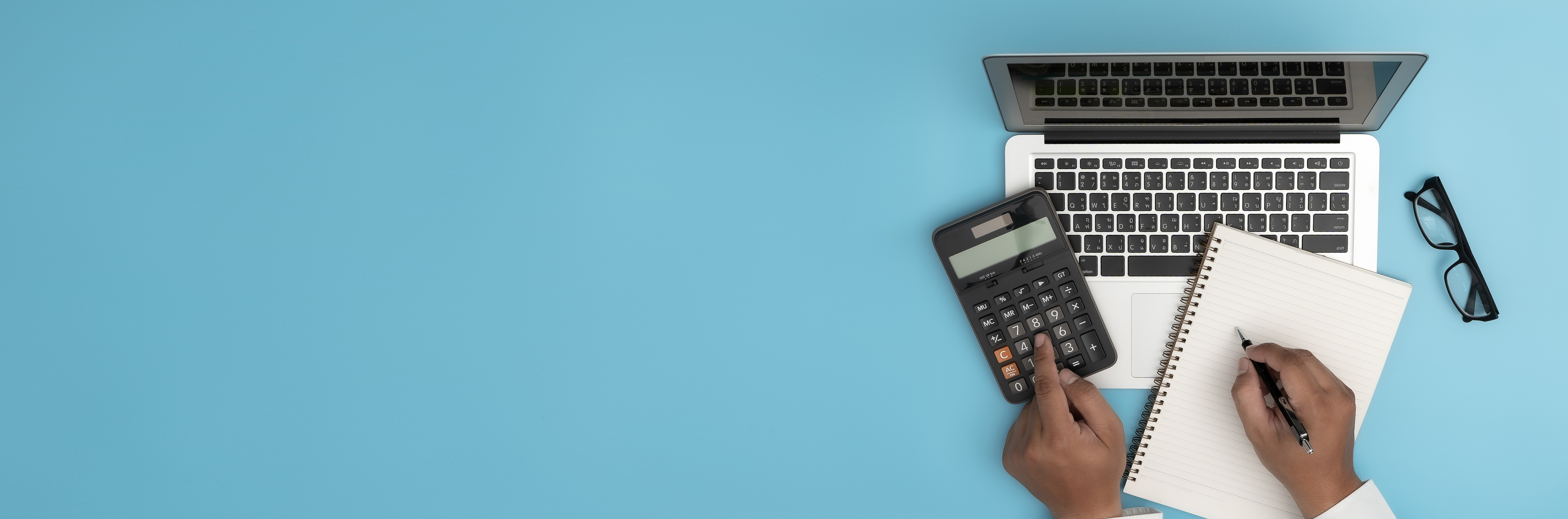 blue background with hands on calculator, notebook, and laptop