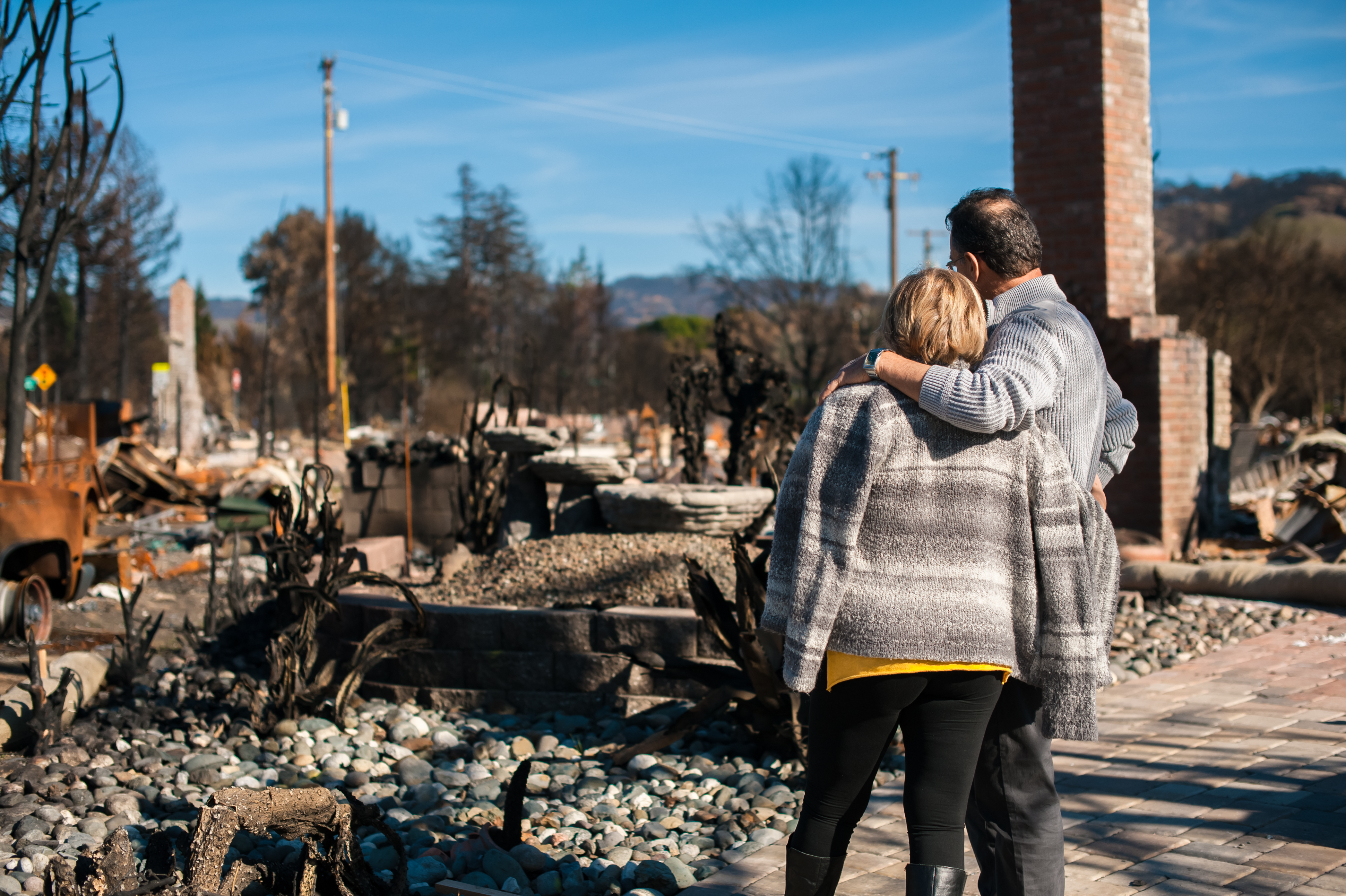 Couple with man's arm around woman's shoulder facing debris 