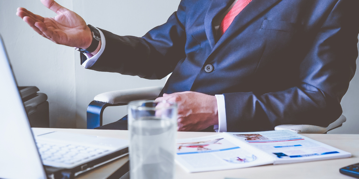 man in suit from face down sitting at table with hand up