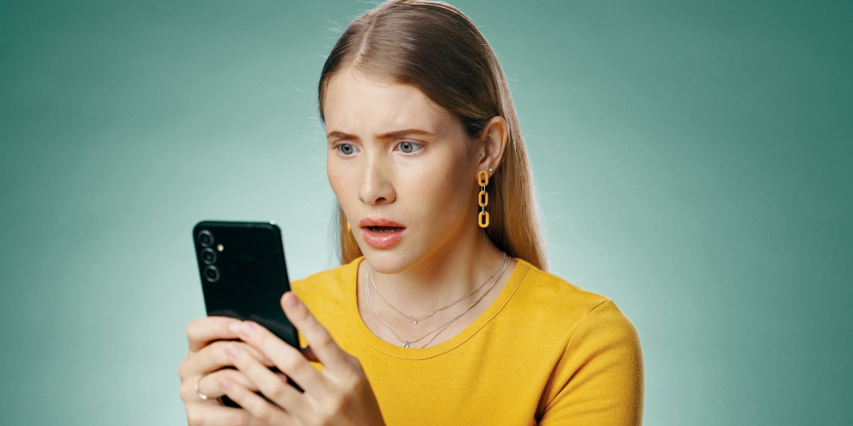 younger woman looking surprised at her phone
