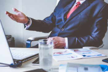 man in suit from face down sitting at table with hand up Banner