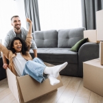 girl sitting in box happy with her hands up while guy pushes box