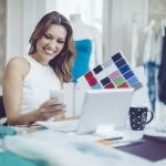Woman smiling at laptop while holding color swatches
