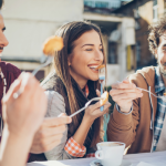 group of young adult friends eating and laughing together 