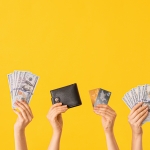 hands holding piggy bank, money, wallet, cards in front of yellow background