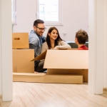 younger white couple talking and smiling to son in moving box