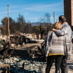 Couple with man's arm around woman's shoulder facing debris 