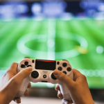 hands holding up gaming controller in front of tv