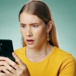 younger woman looking surprised at her phone