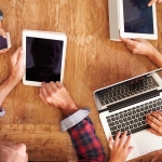 kids and adults at the table with ipads and laptops